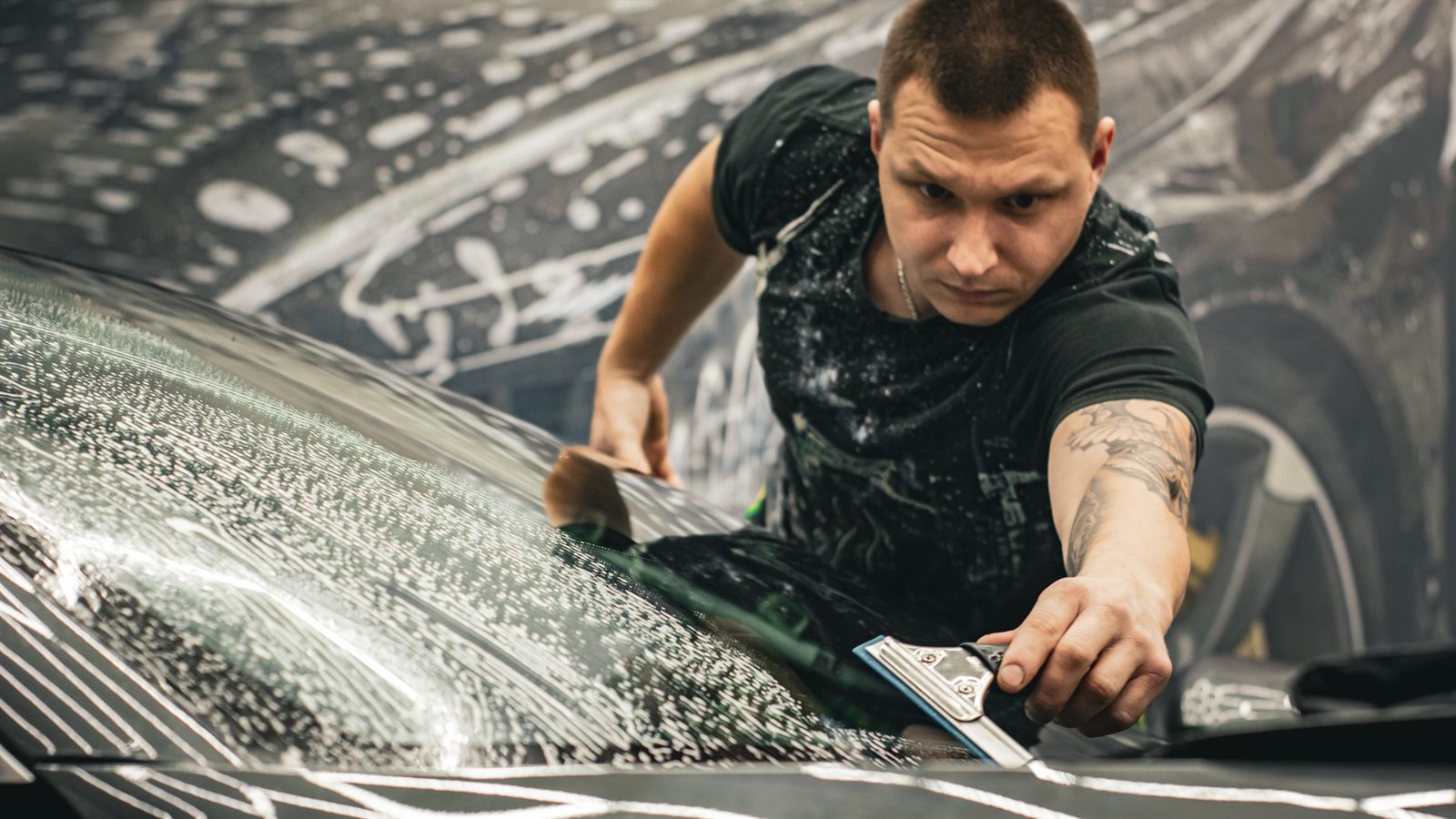 Мастер BlackTon разглаживает плёнку на кузове автомобиля